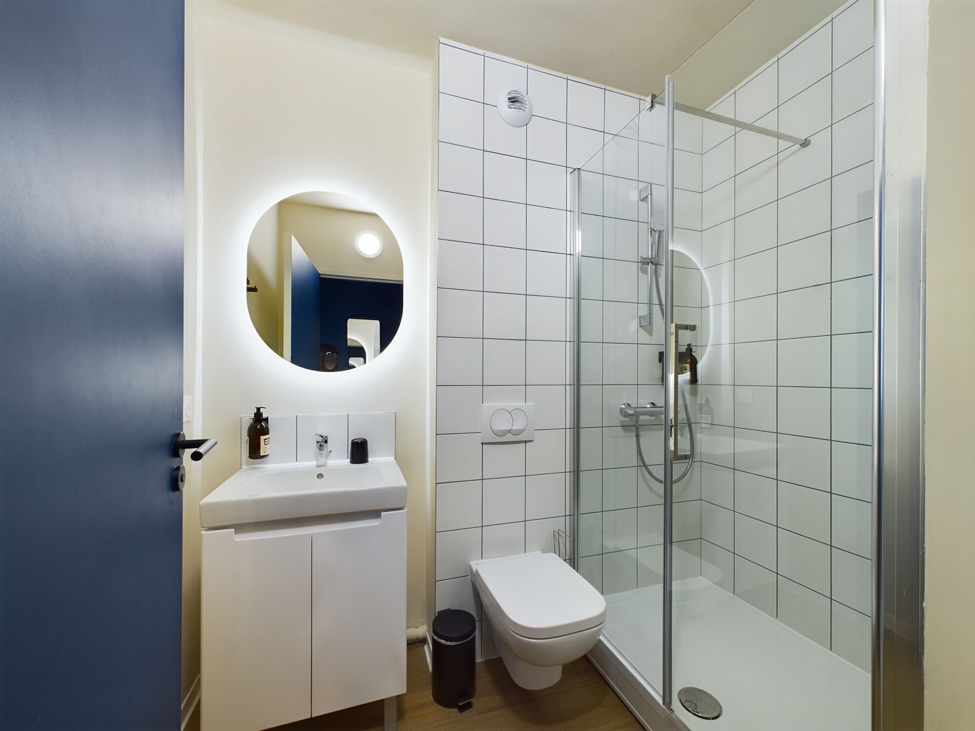A modern bathroom with a white sink, toilet, and glass-enclosed shower.