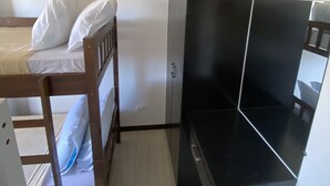 A small, compact room with a bunk bed, a desk, and a wardrobe. - Barkada Room- New Apartment in Palompon (Palompon)