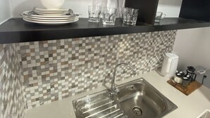 A kitchen with a black countertop, a stainless steel sink, and a tiled backsplash. - Barkada Room- New Apartment in Palompon (Palompon)