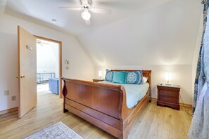 A bedroom with a wooden bed, a nightstand with a lamp, a ceiling fan, and a view of a balcony. - Minutes from KALAHARI and CAMELBACK, 
LAKEFRONT RETREAT!  Sleeps10+, GameRm (Long Pond)