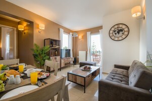 Una sala de estar moderna con un sofá, una mesita de centro y un comedor con provisiones para el desayuno.