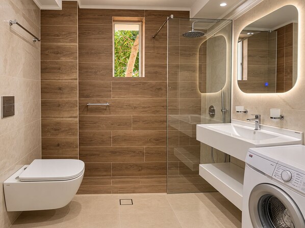 A modern bathroom with a toilet, shower, and washing machine. - Artdeco Luxury Suites (Chania)