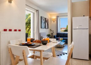 A modern kitchen with a dining area, a refrigerator, and a view of the outdoors. - Artdeco Luxury Suites (Chania)