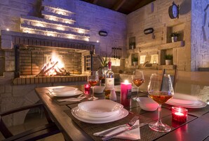 Mesa lista para dos personas con chimenea de ladrillo, velas y copas de vino.