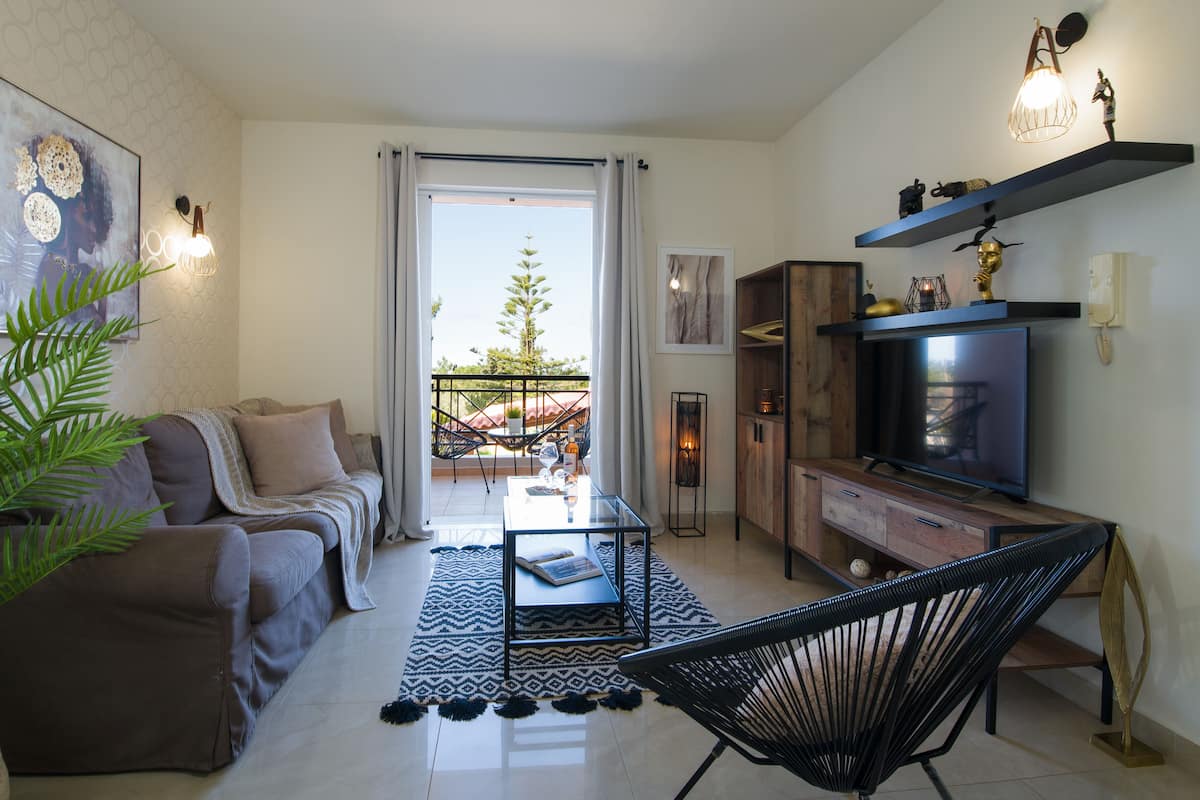 Un salon avec un canapé, une table basse, un téléviseur et un balcon offrant une vue agréable.