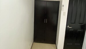 Une pièce avec une armoire noire, un climatiseur blanc et une porte fermée.