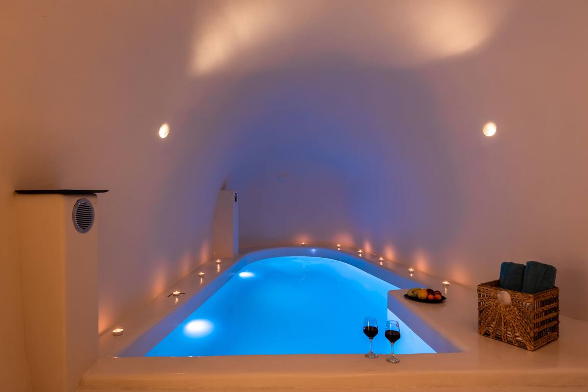 A spa tub with a blue light, candles, and a fruit basket.