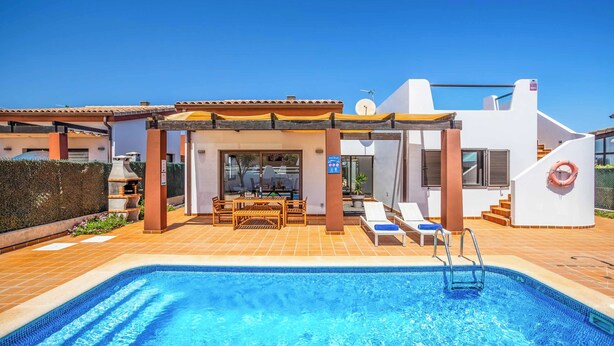A modern pool area with a clear blue pool, a covered seating area, and a staircase leading to an upper level.