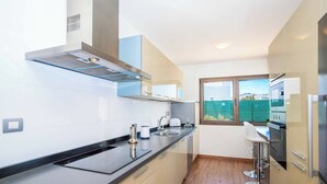A modern kitchen with a black countertop, stainless steel appliances, and a window with a view.