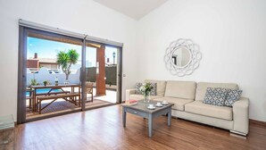 A modern living room with a sofa, coffee table, and a view of a pool and outdoor area.