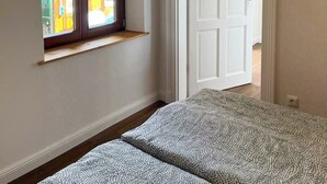 A room with a large window, a door, and a bed.