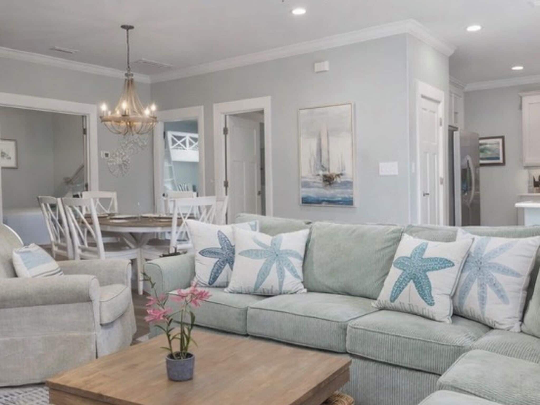 A living room with a light-colored sofa, a wooden coffee table, and a chandelier.