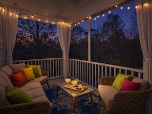 A covered outdoor seating area with a ceiling fan, string lights, and a view of trees. - 6015 Rookery 3 Tropic Like is hot (Gulf Shores)