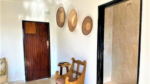 A hallway with a wooden door, a wooden chair, and three wall-mounted decorative plates. - Cosy studio with kitchenette in Norton - 2120 (Norton)
