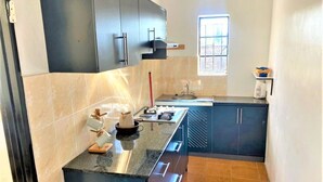 A kitchen with dark cabinets, a granite countertop, and a window providing natural light. - Cosy studio with kitchenette in Norton - 2120 (Norton)