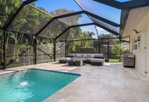 Un área de piscina techada al aire libre, con zona de estar integrada y vista a la vegetación circundante.