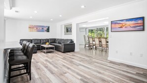 A modern living room with a sectional sofa, a dining area with a table and chairs, and artwork on the walls. - Naples Dream Escape 4BR Home, heated pool, 10min from Beach (Naples)