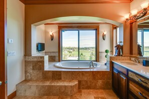 Un baño moderno con una bañera grande, vistas al exterior y un tocador con espejo.