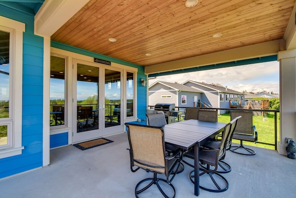 Un patio cubierto con techo de madera, una mesa con sillas y vistas a casas vecinas.