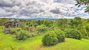 Una casa rustica circondata da vegetazione lussureggiante e un cielo nuvoloso.
