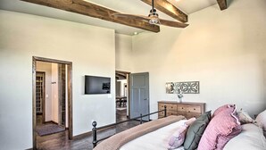 A bedroom with a large bed, a wooden ceiling beam, a wardrobe, and a door leading to a bathroom. - Pastoral Elgin Escape w/ Covered Patio & Grill! (Elgin)