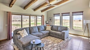 A spacious living room with a large sectional sofa, a ceiling fan, and large windows offering a view of a mountainous landscape. - Pastoral Elgin Escape w/ Covered Patio & Grill! (Elgin)