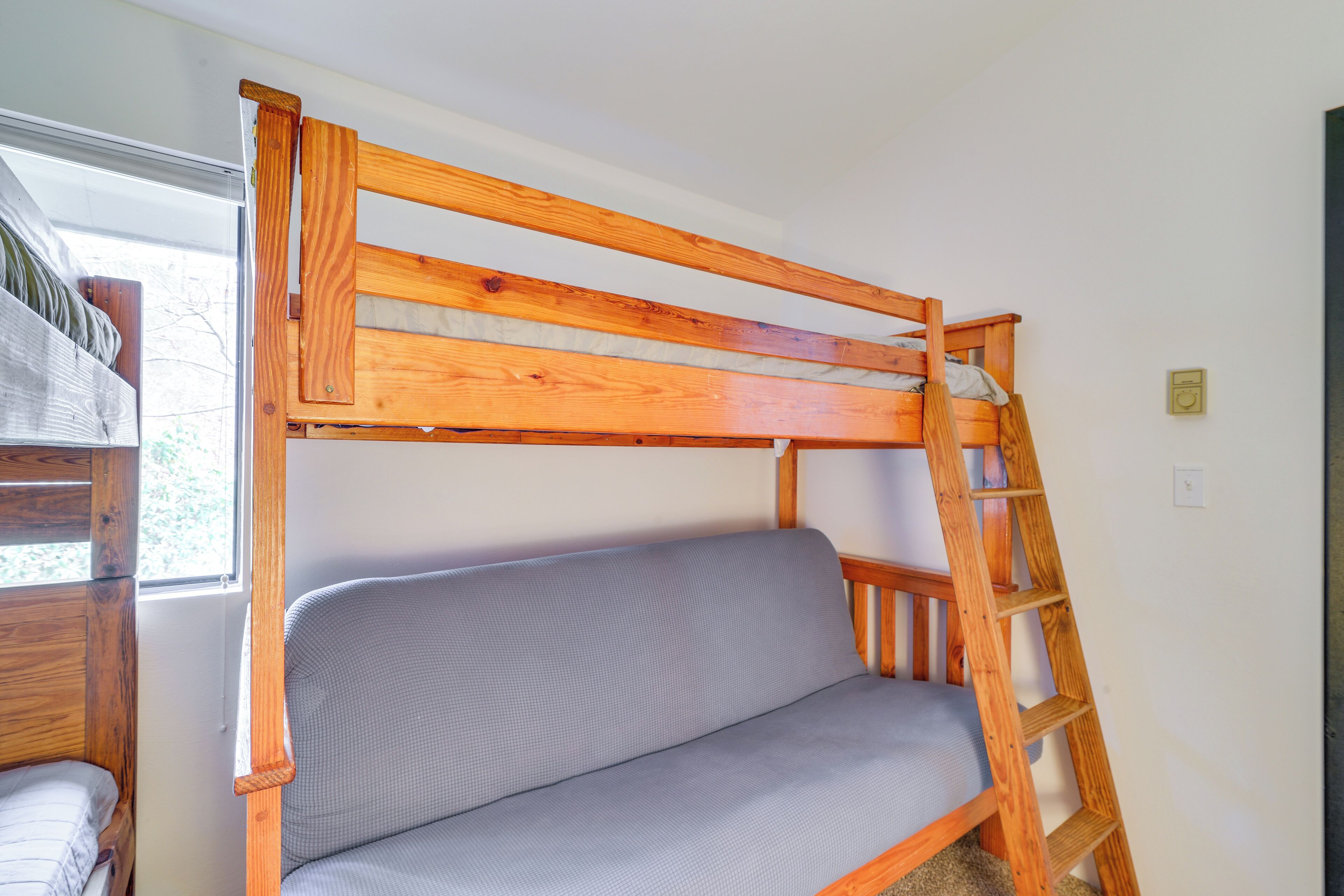 A bunk bed with a ladder, a window, and a small shelf.