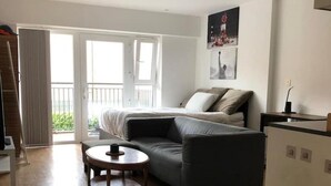 A modern, well-lit room with a sofa, a small round table, and a refrigerator.