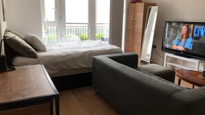A bedroom with a bed, a TV, a sofa, and a wooden table.