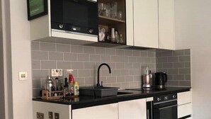 A modern kitchen with white cabinetry, a black countertop, and a stainless steel range hood.