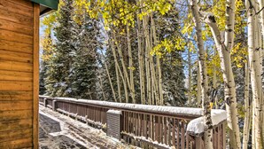 A wooden deck with a metal railing, surrounded by snow-covered trees and a clear sky. - The Cottages: Ski-in/ski-out Condo at Eagle Point! (Beaver)