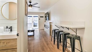 A modern kitchen with a white countertop, black stools, and a ceiling fan. - The Cottages: Ski-in/ski-out Condo at Eagle Point! (Beaver)