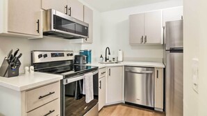 A modern kitchen with stainless steel appliances, white cabinetry, and a built-in oven. - The Cottages: Ski-in/ski-out Condo at Eagle Point! (Beaver)