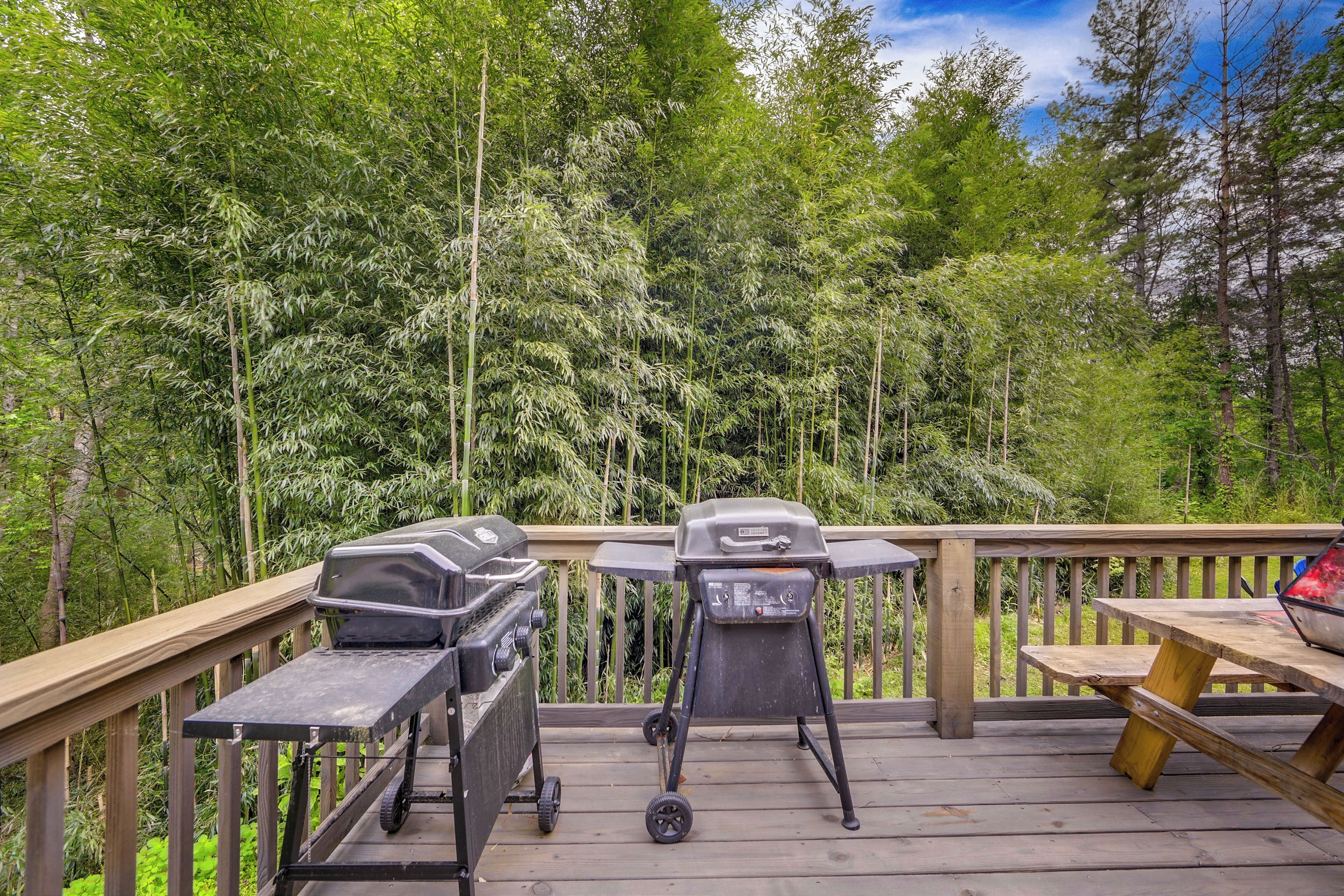 A wooden deck with two barbecue grills and a picnic table.