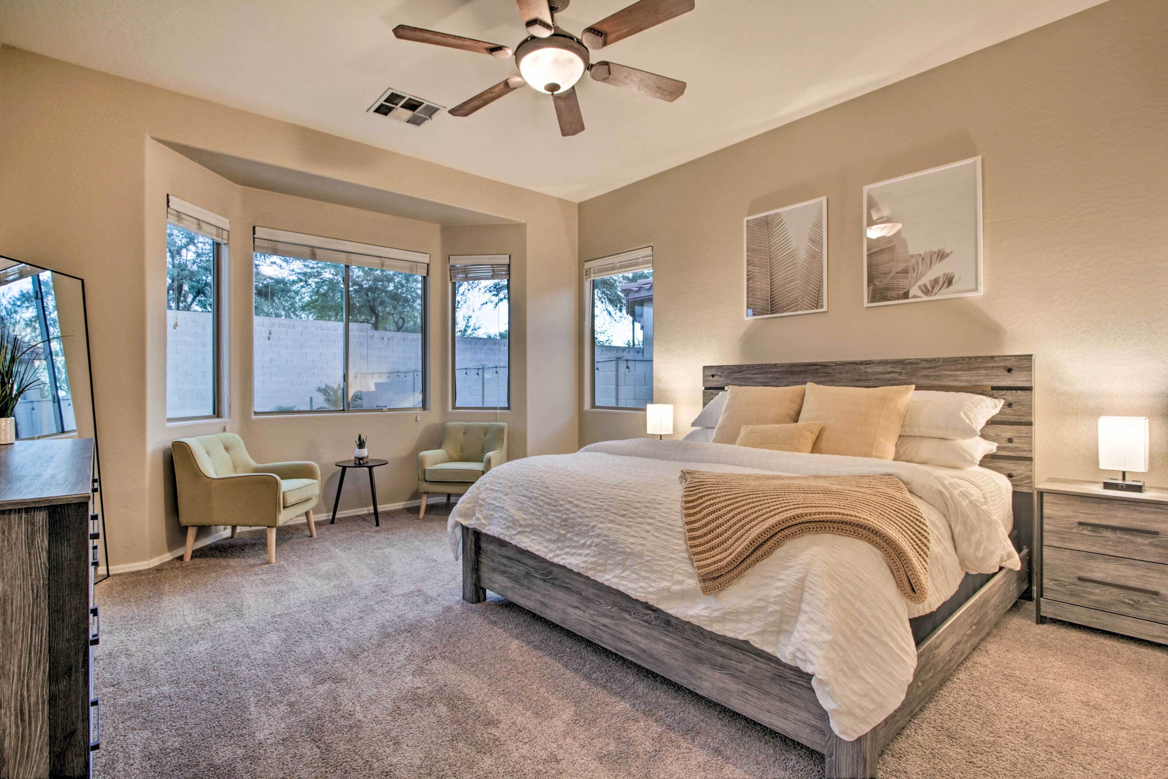 Une chambre à coucher avec un grand lit, un ventilateur de plafond et de nombreuses fenêtres.