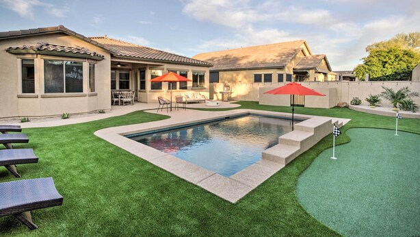 A backyard with a swimming pool, artificial grass, and outdoor furniture. - Pool & Game Room: Home in Goodyear Near Golfing (Goodyear)