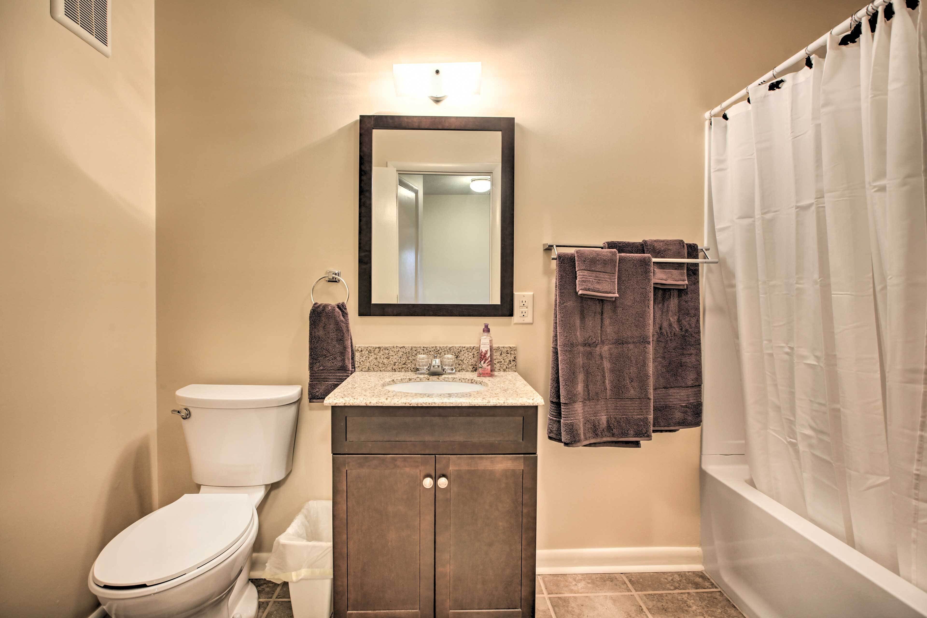 A bathroom with a toilet, sink, mirror, and shower curtain.