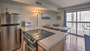 A modern kitchen with stainless steel appliances, a built-in stove, and a dining area with a view of the balcony.