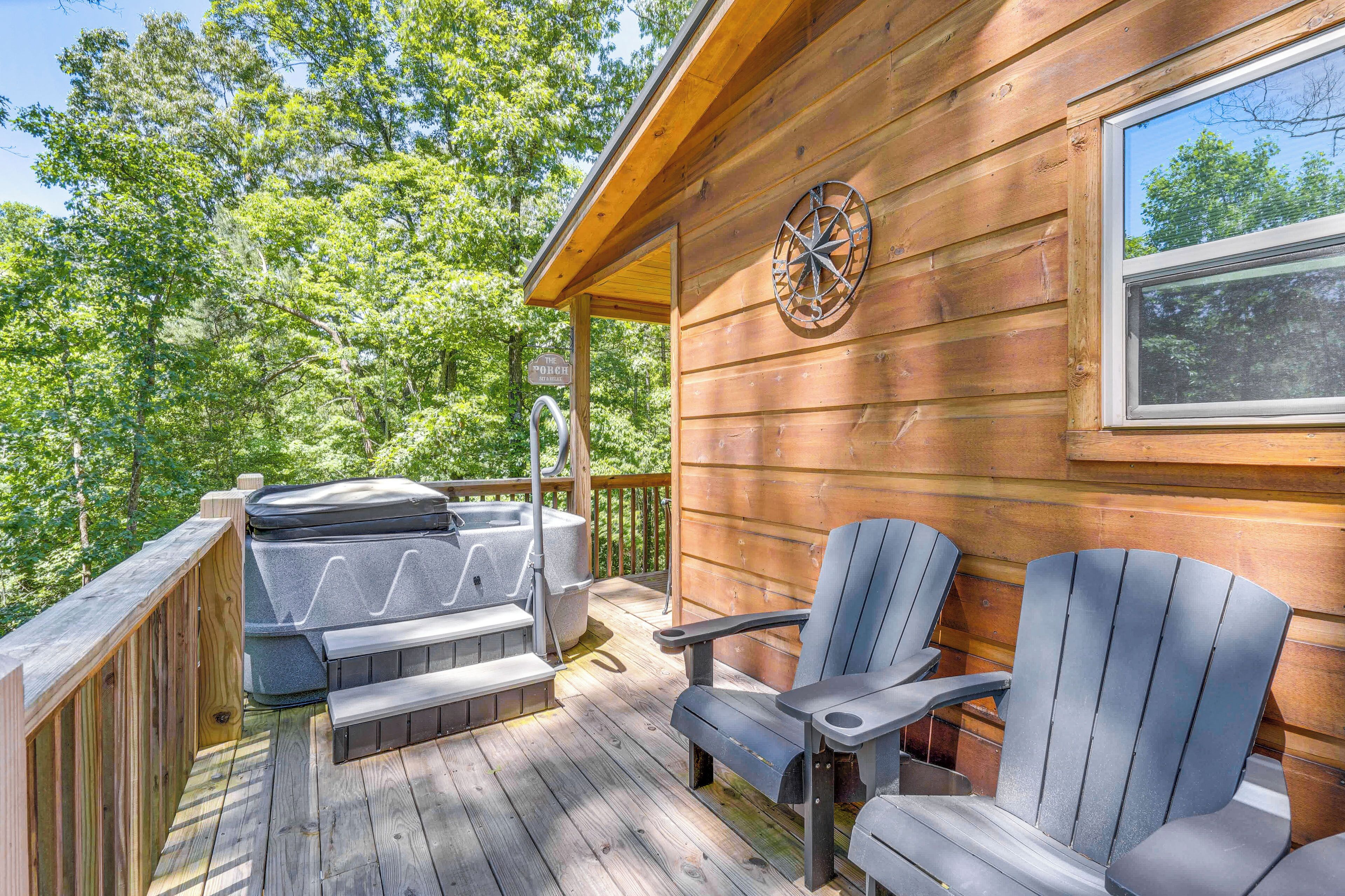 A wooden deck with Adirondack chairs, a hot tub, and a compass wall decoration.