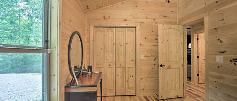 Una habitación de cabaña de madera con un ventanal grande, un espejo, una mesa y una cama.