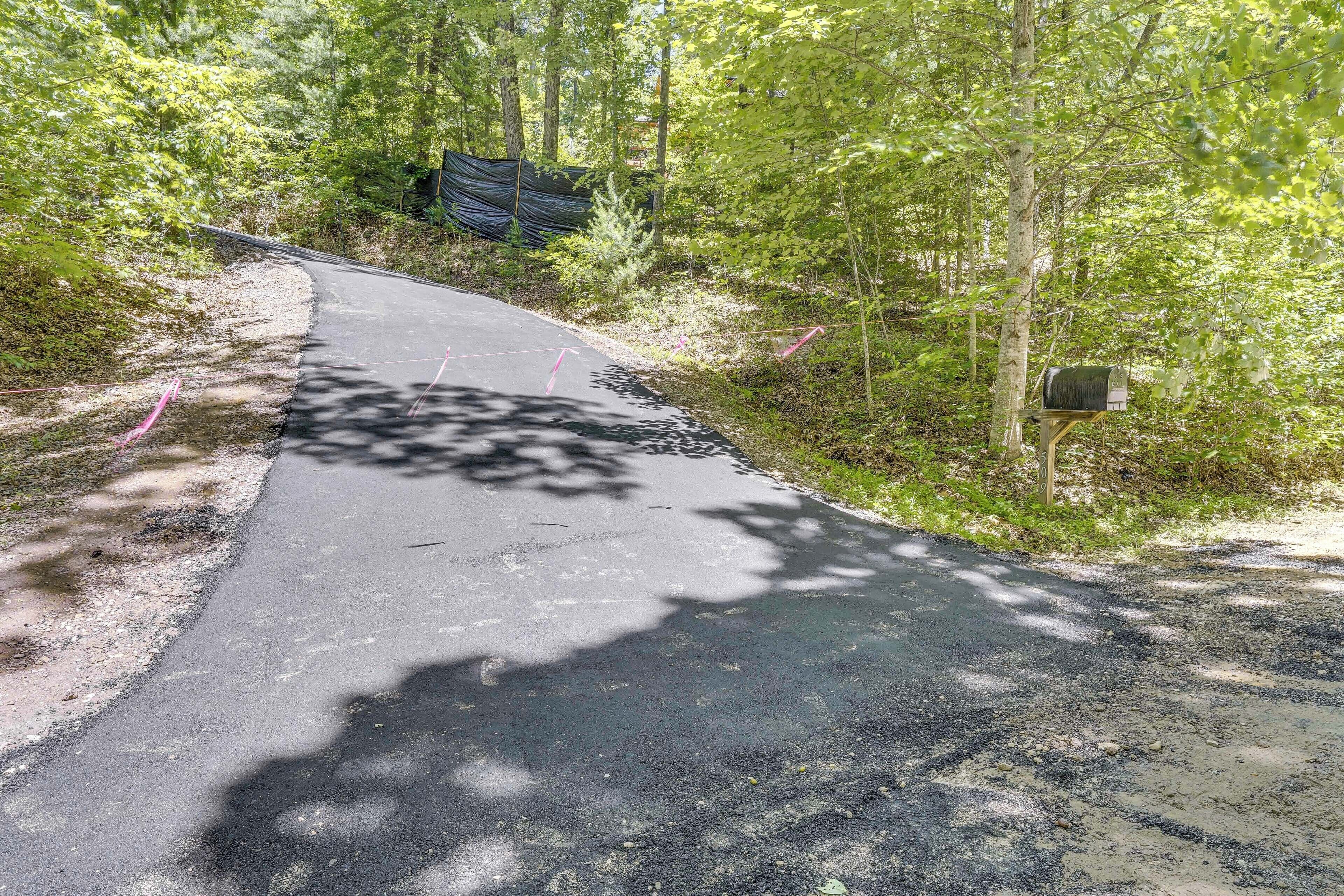 Une route asphaltée qui serpente à travers une zone boisée, avec une boîte aux lettres sur le côté droit.