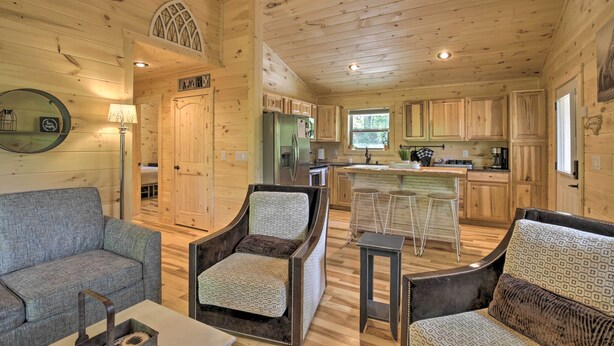 Interior acogedor de una cabaña con comedor, cocina y sala de estar con sofá y sillones.