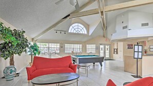A spacious indoor area with a pool table, red sofas, and a large potted plant. - Laguna Bay Townhome w/ Pool Access & More! (Kissimmee)