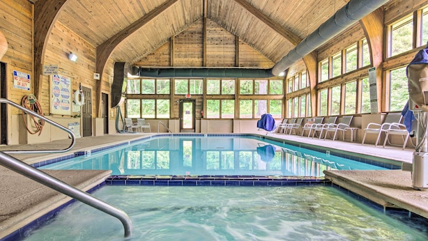 A large indoor swimming pool with a wooden ceiling and windows.