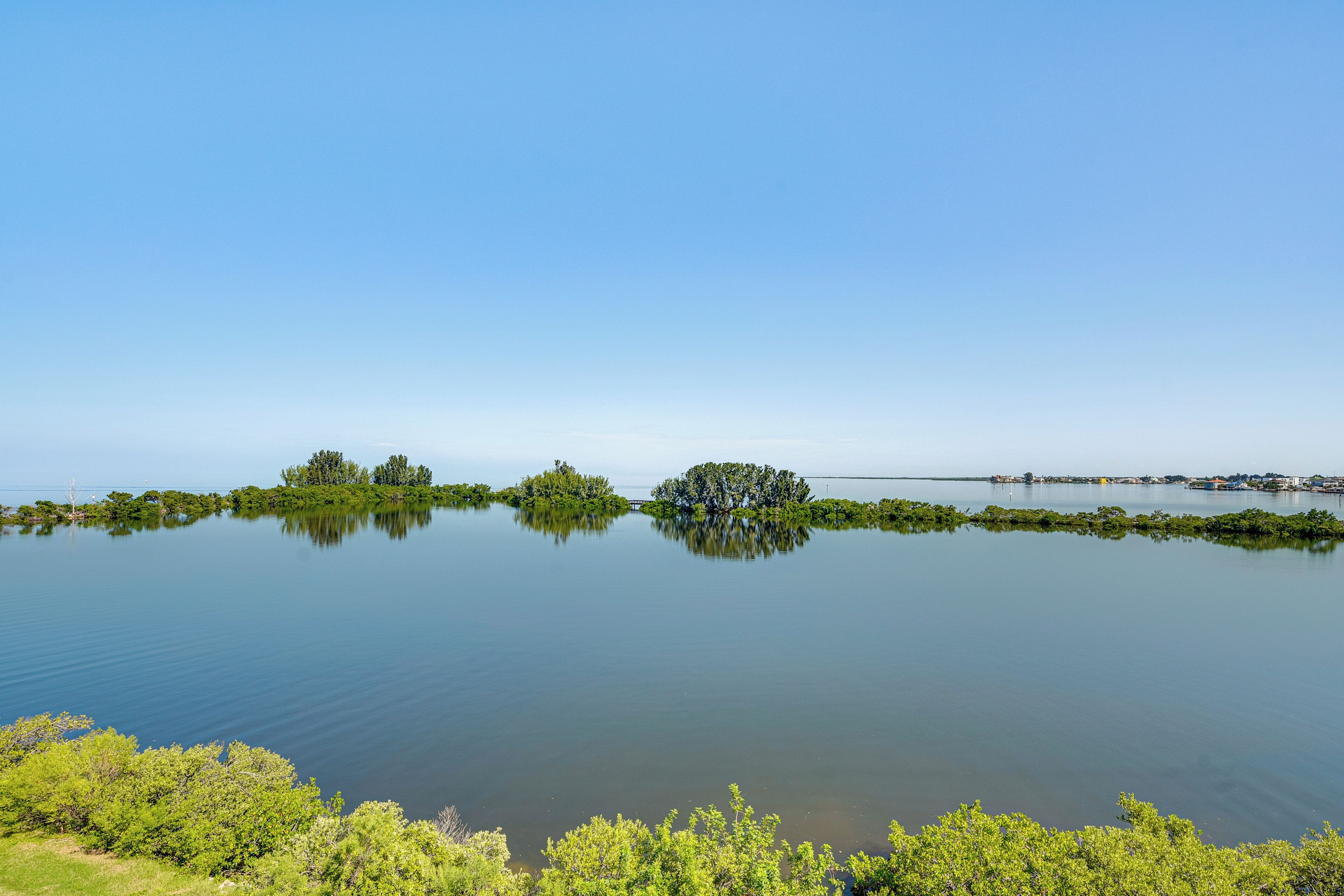 A calm lake with several small islands and a distant bridge.