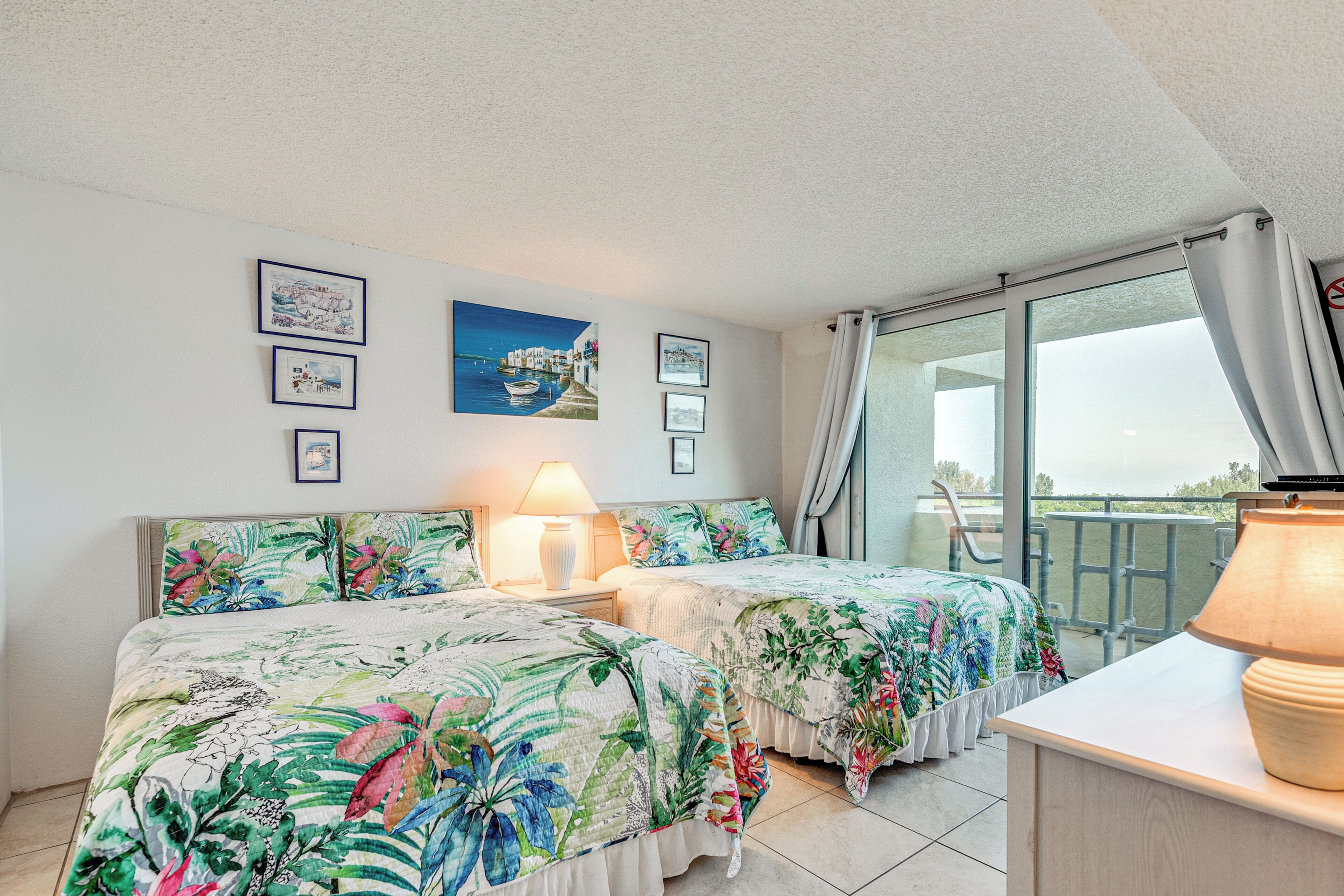 A hotel room with two beds, a balcony, and a view of the sea.