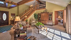 Un salon spacieux avec un escalier en bois, une grande fenêtre et un coin salon confortable.