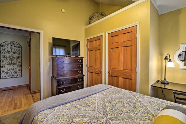 A bedroom with a bed, dresser, and two wooden doors. - Private Family Home w/ Deck, Porch + Forest Views! (Oakland)