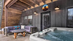 An outdoor patio area with a hot tub, a purple sofa, and a wooden table. - Modern Lead A-frame w/ Hot Tub: Hike, Bike & Atv! (Lead)