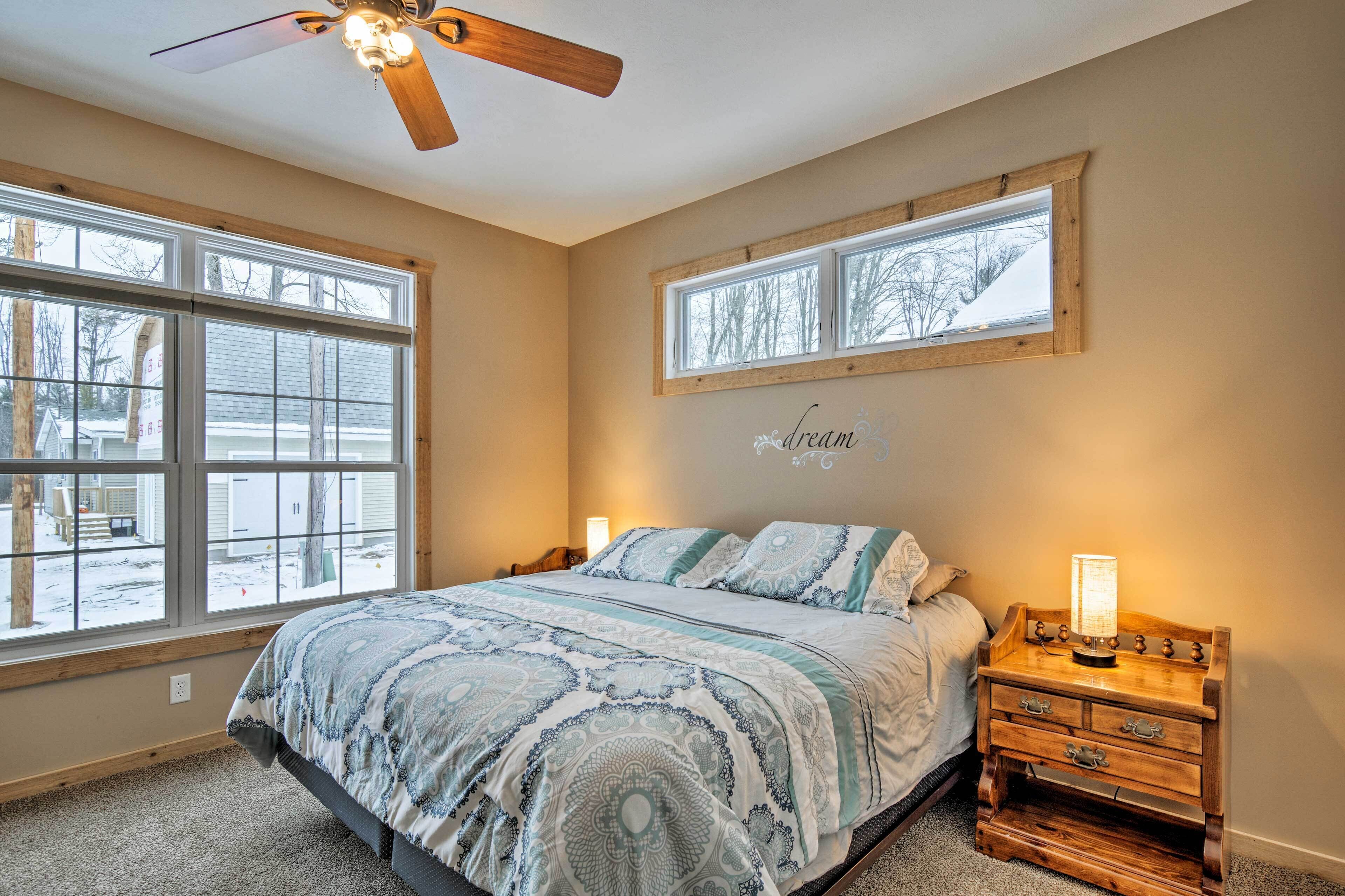 A bedroom with a bed, a nightstand, a wall-mounted shelf, and a ceiling fan.